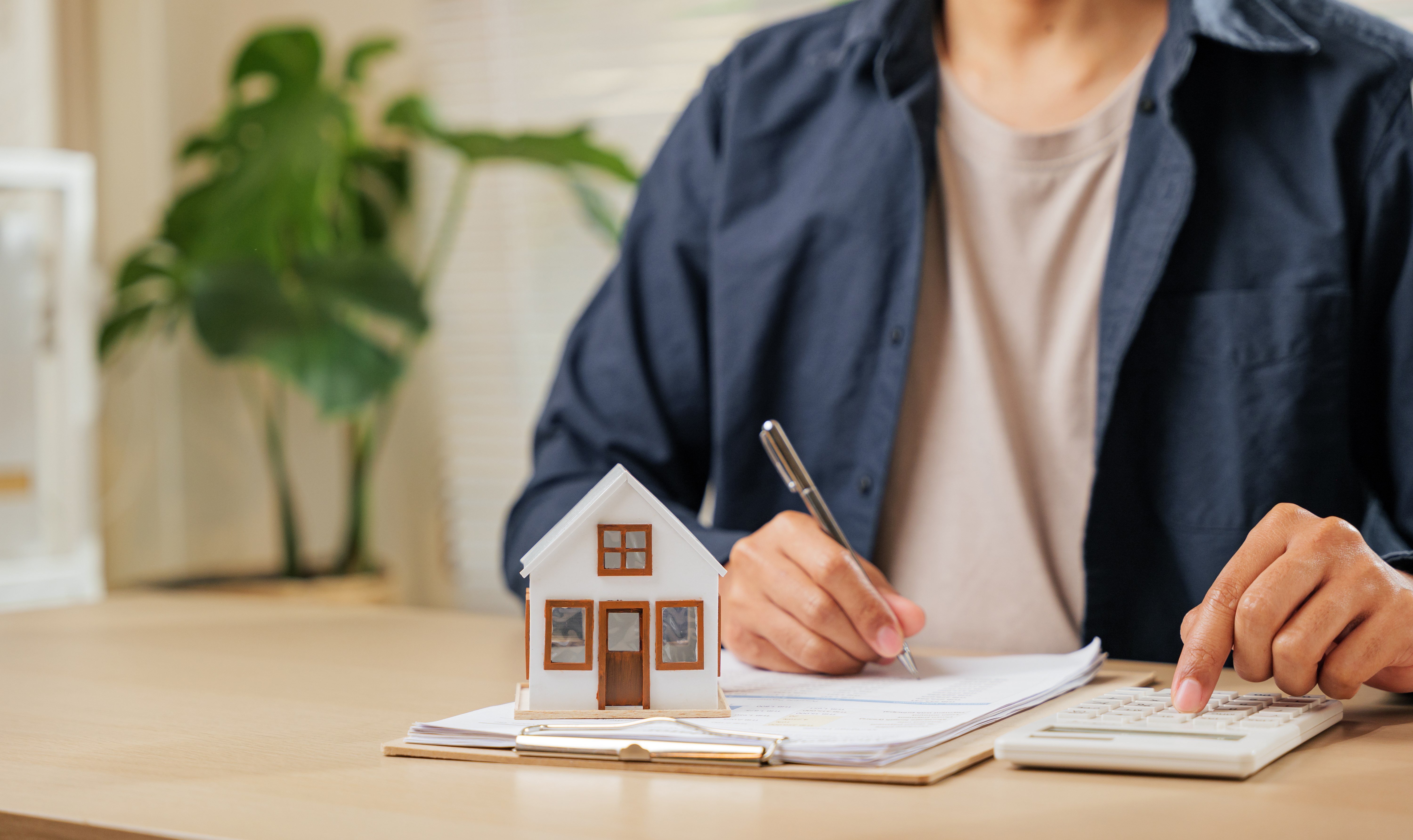 Person calculating property taxes with house model